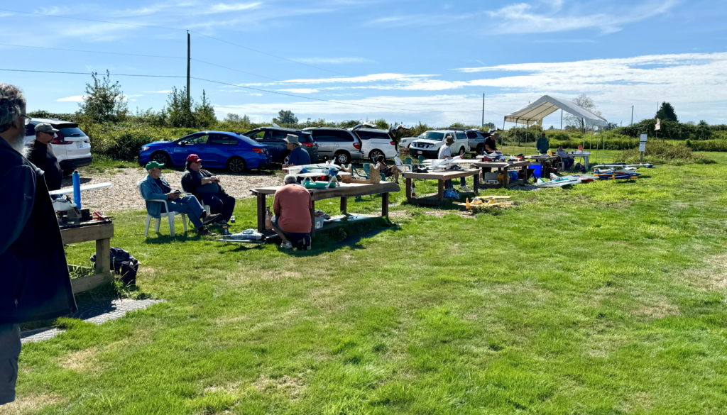 Aeromodellers sitting in the pits area on a sunny day.